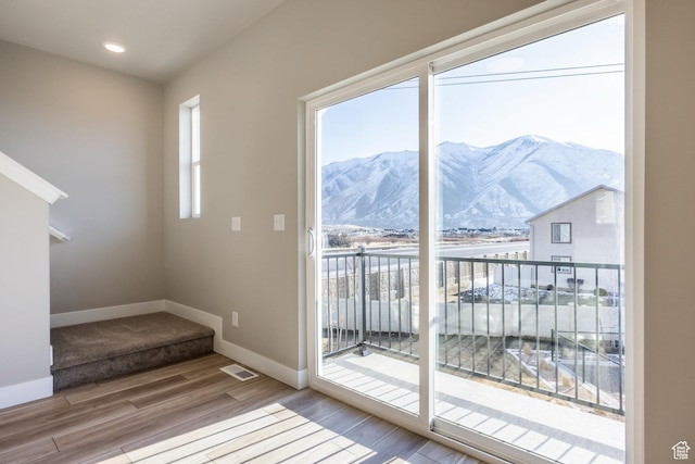 doorway to outside with hardwood / wood-style flooring, a mountain view, and a wealth of natural light