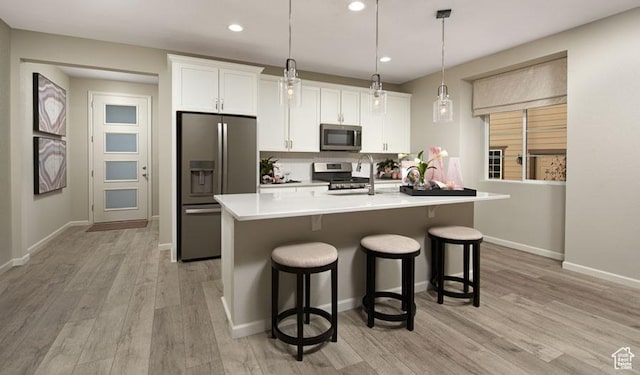 2144 W 3930 S Unit 21, Hurricane, UT 84737 - kitchen featuring appliances with stainless steel finishes, pendant lighting, white cabinetry, an island with sink, and light hardwood / wood-style flooring