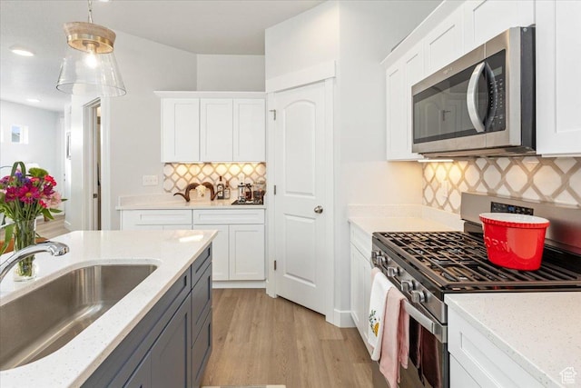 1088 N Freeman Dr, Saratoga Springs, UT 84045 - kitchen featuring white cabinets, stainless steel appliances, a sink, light wood-style floors, and decorative backsplash