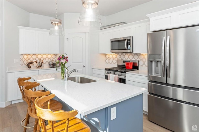 1088 N Freeman Dr, Saratoga Springs, UT 84045 - kitchen with an island with sink, stainless steel appliances, a sink, decorative backsplash, and white cabinetry