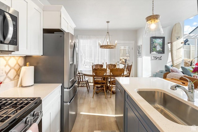 1088 N Freeman Dr, Saratoga Springs, UT 84045 - kitchen featuring light stone counters, stainless steel appliances, a sink, light wood-type flooring, and white cabinetry