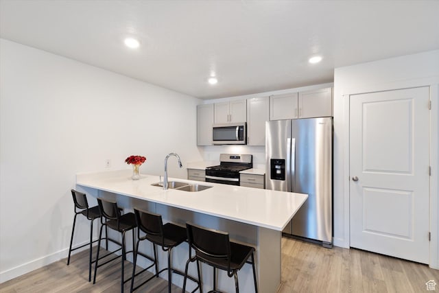 kitchen featuring stainless steel appliances, sink, a breakfast bar area, and kitchen peninsula