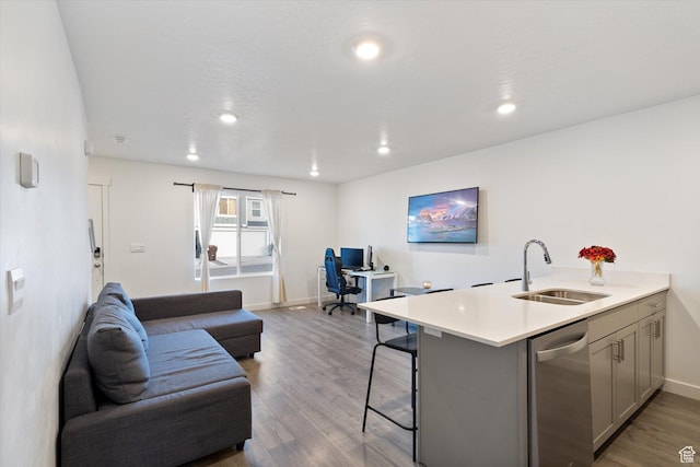 kitchen featuring a breakfast bar, sink, gray cabinetry, kitchen peninsula, and light hardwood / wood-style flooring