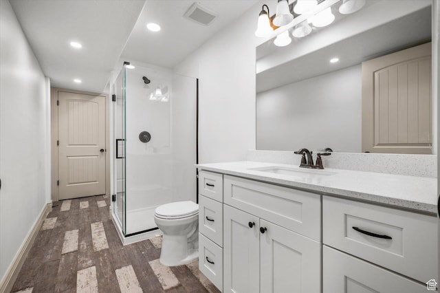 bathroom featuring vanity, toilet, hardwood / wood-style floors, and a shower with shower door