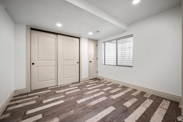 unfurnished bedroom featuring dark wood-type flooring, a closet, and a textured ceiling