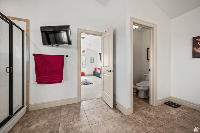 bathroom featuring a shower with door, vaulted ceiling, tile patterned flooring, and toilet