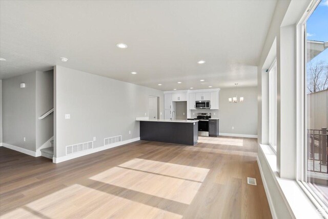 unfurnished living room featuring visible vents, a chandelier, and light wood-style flooring
