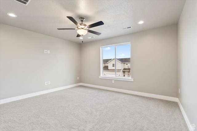 empty room with baseboards, visible vents, carpet floors, ceiling fan, and a textured ceiling