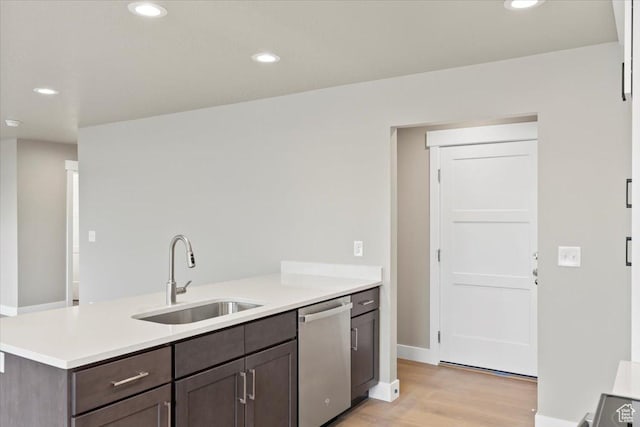 kitchen with a sink, stainless steel dishwasher, light wood-style flooring, and light countertops