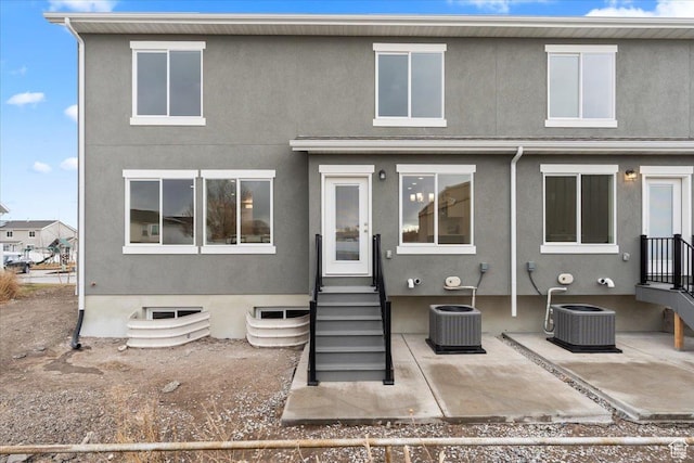 back of house featuring cooling unit, a patio area, entry steps, and stucco siding
