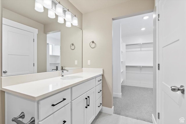 bathroom featuring vanity, a walk in closet, and baseboards