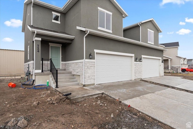 view of front of home featuring stone siding, stucco siding, driveway, and a garage