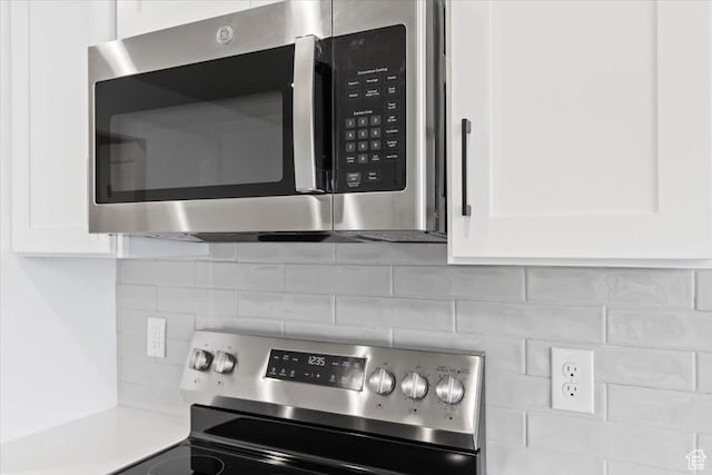 interior details featuring decorative backsplash, appliances with stainless steel finishes, white cabinets, and light countertops