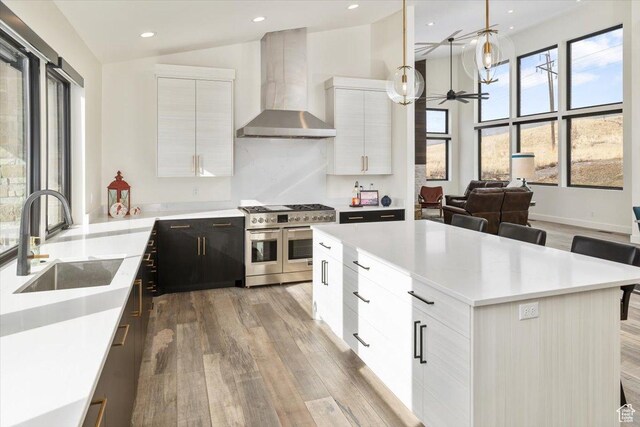 3450 N 1930 E, North Logan, UT 84341 - kitchen featuring sink, pendant lighting, wall chimney range hood, range with two ovens, and white cabinets