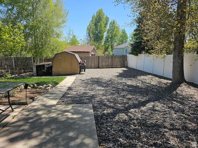 fenced backyard featuring a storage unit, an outbuilding, and a patio
