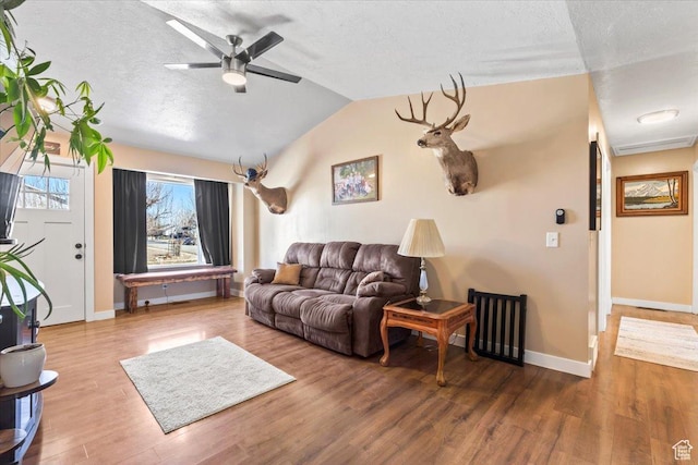 living area featuring a textured ceiling, wood finished floors, ceiling fan, lofted ceiling, and baseboards