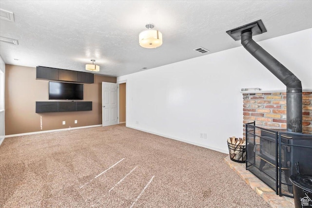 living room featuring a wood stove, carpet, a textured ceiling, and baseboards