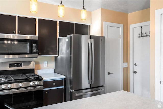 kitchen featuring stainless steel appliances, light countertops, and decorative light fixtures
