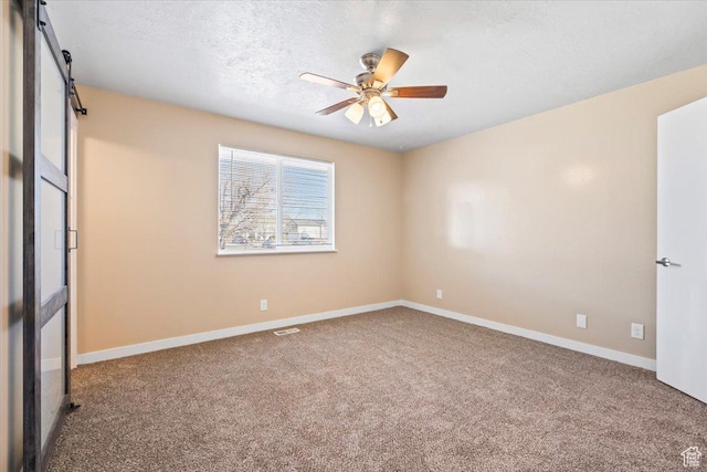 unfurnished room with carpet, a ceiling fan, baseboards, and a textured ceiling