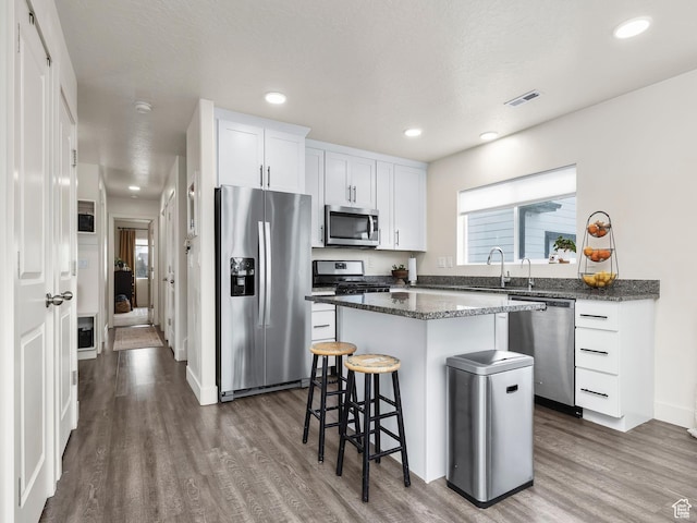 1802 E Magnolia Cir, Eagle Mountain, UT 84005 - kitchen featuring white cabinetry, dark stone countertops, stainless steel appliances, dark hardwood / wood-style floors, and a center island