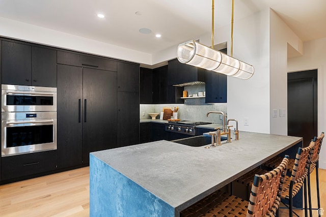 99 W S Temple St S Unit 2201, Salt Lake City, UT 84101 - kitchen featuring double oven, light hardwood / wood-style flooring, sink, a breakfast bar area, and tasteful backsplash