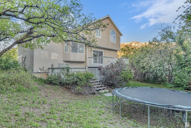 2152 E 3325 N, Layton, UT 84040 - exterior space featuring a trampoline, stairs, a wooden deck, stucco siding, and a yard