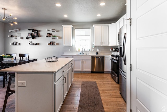 1038 W Regatta Ln, Stansbury Park, UT 84074 - kitchen featuring sink, a breakfast bar area, white cabinetry, stainless steel appliances, and a center island