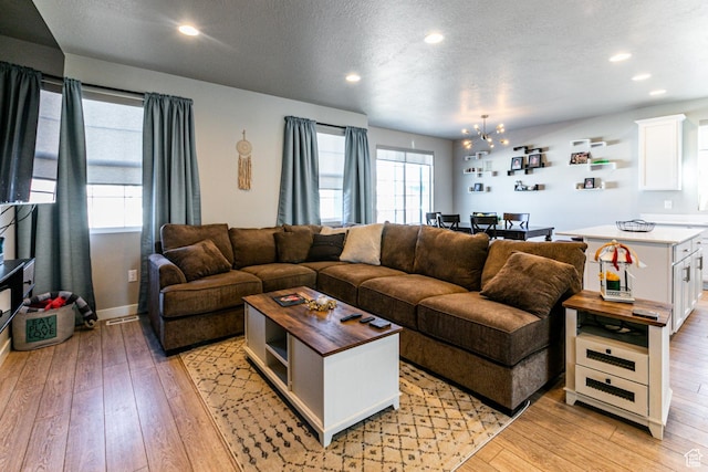 1038 W Regatta Ln, Stansbury Park, UT 84074 - living room featuring an inviting chandelier, a textured ceiling, and light hardwood / wood-style flooring