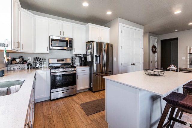 1038 W Regatta Ln, Stansbury Park, UT 84074 - kitchen with a breakfast bar area, stainless steel appliances, white cabinets, and a kitchen island