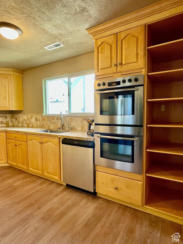 255 W Main St, Mount Pleasant, UT 84647 - kitchen featuring appliances with stainless steel finishes, light countertops, light wood-style flooring, decorative backsplash, and a textured ceiling