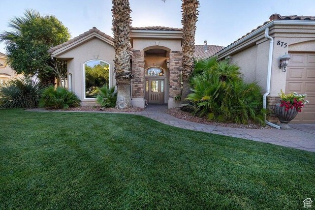 mediterranean / spanish-style house with a garage and a front lawn