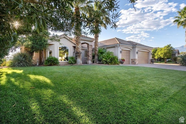 mediterranean / spanish home featuring a garage and a front yard