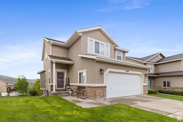 840 N Great View Dr E, Morgan, UT 84050 - townhome / multi-family property with brick siding, stucco siding, a front yard, concrete driveway, and an attached garage