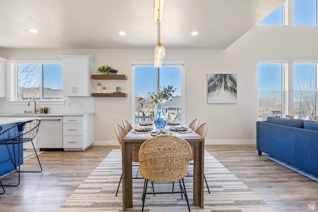 dining space featuring light wood finished floors, baseboards, and a textured ceiling