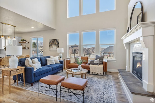 living area featuring recessed lighting, baseboards, wood finished floors, and a tile fireplace