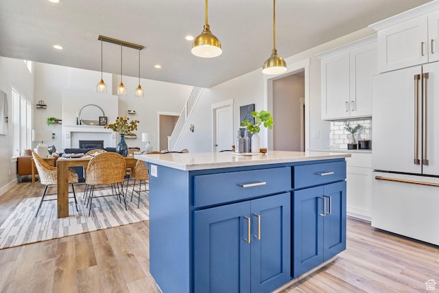 kitchen featuring blue cabinets, high end white refrigerator, white cabinetry, and light wood finished floors