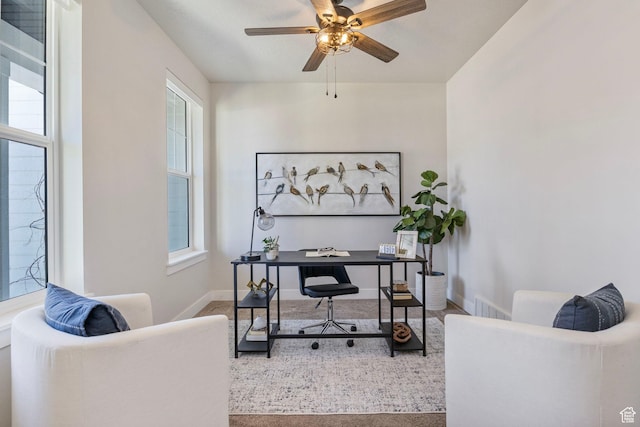 carpeted home office with a ceiling fan, a healthy amount of sunlight, visible vents, and baseboards
