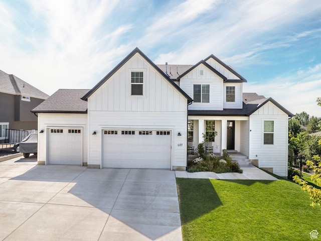 modern farmhouse with a shingled roof, fence, driveway, board and batten siding, and a front yard