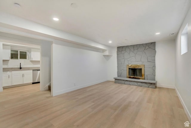 320 S 7 E, Tooele, UT 84074 - unfurnished living room with light wood-type flooring, a sink, a stone fireplace, baseboards, and recessed lighting