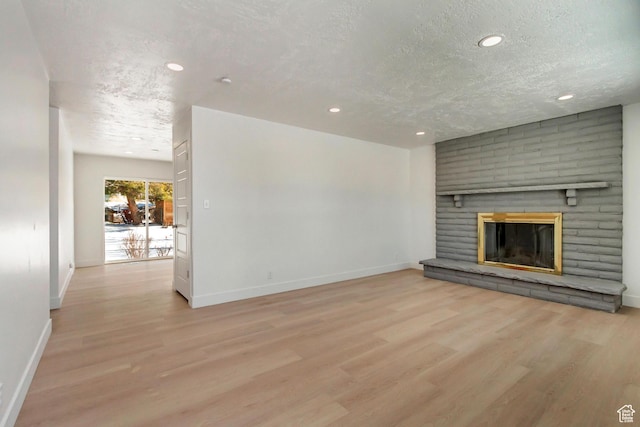 320 S 7 E, Tooele, UT 84074 - unfurnished living room with baseboards, light wood-style flooring, a textured ceiling, a fireplace, and recessed lighting