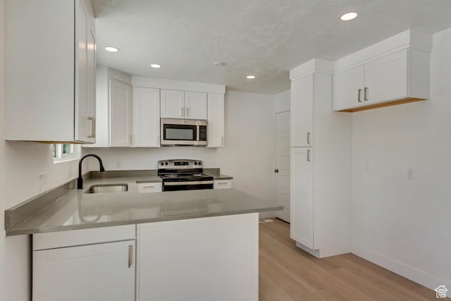 320 S 7 E, Tooele, UT 84074 - kitchen with stainless steel appliances, a sink, light wood-type flooring, a peninsula, and white cabinets