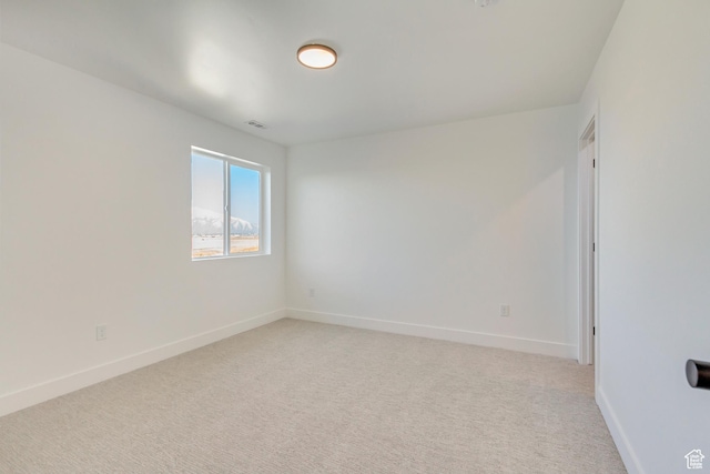 empty room with visible vents, baseboards, and light carpet