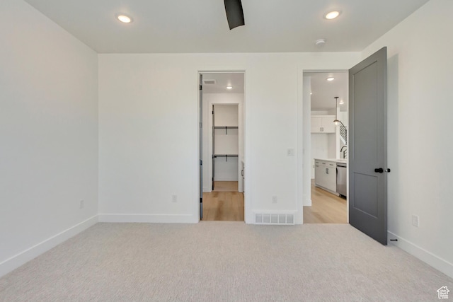 unfurnished bedroom featuring a spacious closet, light colored carpet, baseboards, visible vents, and recessed lighting