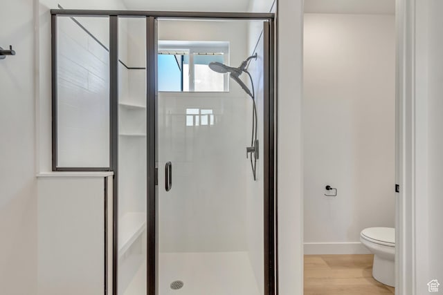 full bathroom featuring wood finished floors, baseboards, a shower stall, and toilet