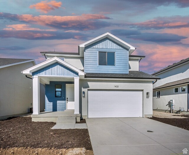 view of front facade with board and batten siding, a garage, concrete driveway, and covered porch
