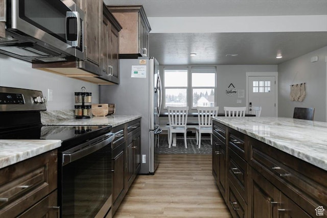 356 W Rendezvous Way, Garden City, UT 84028 - kitchen with appliances with stainless steel finishes, dark brown cabinets, light stone counters, and light hardwood / wood-style flooring