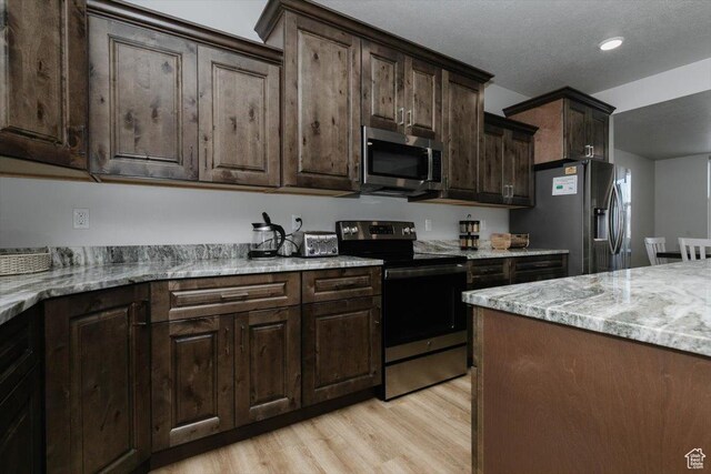 356 W Rendezvous Way, Garden City, UT 84028 - kitchen with dark brown cabinetry, stainless steel appliances, light stone countertops, and light wood-type flooring