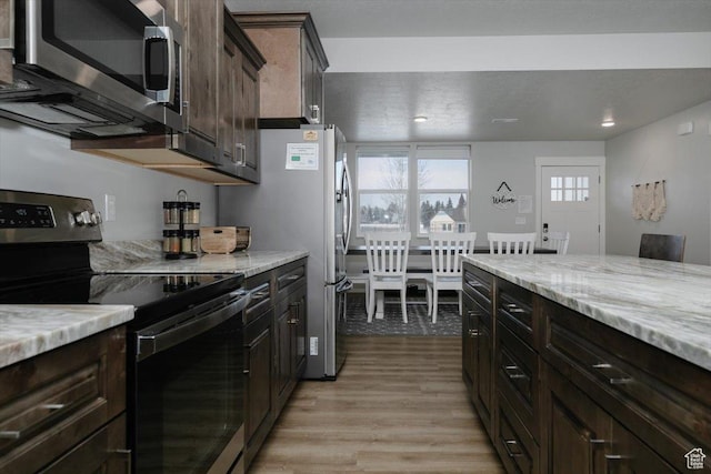 356 W Rendezvous Way, Garden City, UT 84028 - kitchen with dark brown cabinetry, stainless steel appliances, light stone countertops, and light hardwood / wood-style floors