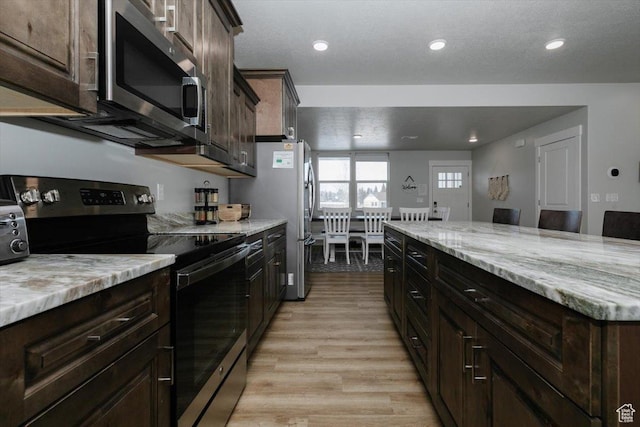 356 W Rendezvous Way, Garden City, UT 84028 - kitchen with appliances with stainless steel finishes, dark brown cabinetry, light stone countertops, a textured ceiling, and light hardwood / wood-style flooring