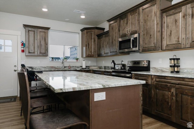356 W Rendezvous Way, Garden City, UT 84028 - kitchen featuring dark brown cabinets, stainless steel appliances, a center island, and a breakfast bar